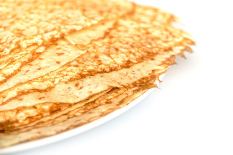 Close up on a stack of crepes (french pancakes) on a plate, white background