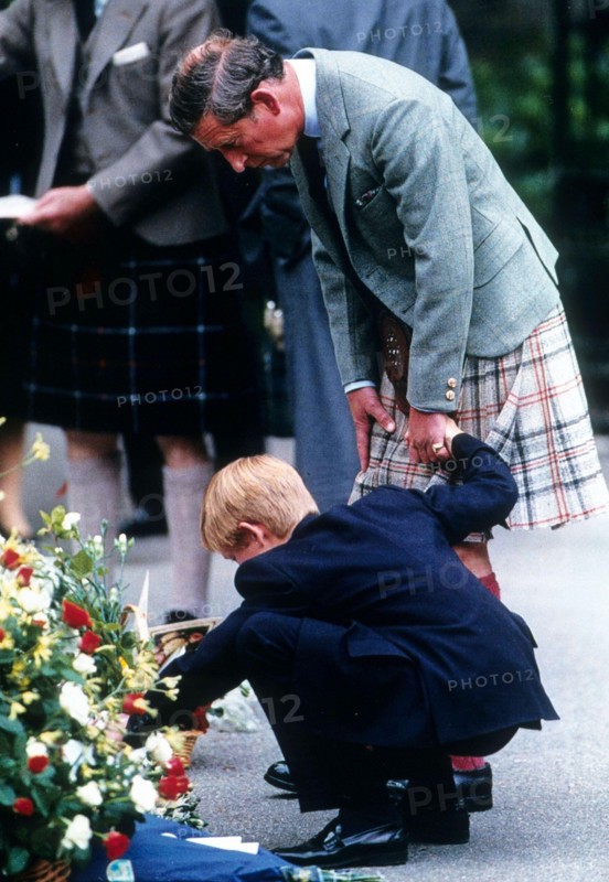 Prince Charles, Prince of Wales, holds the hand of Prince Harry as they view bouquets of flowers left in memory of Diana, Princess of Wales in September 1997 in Balmoral, Scotland.