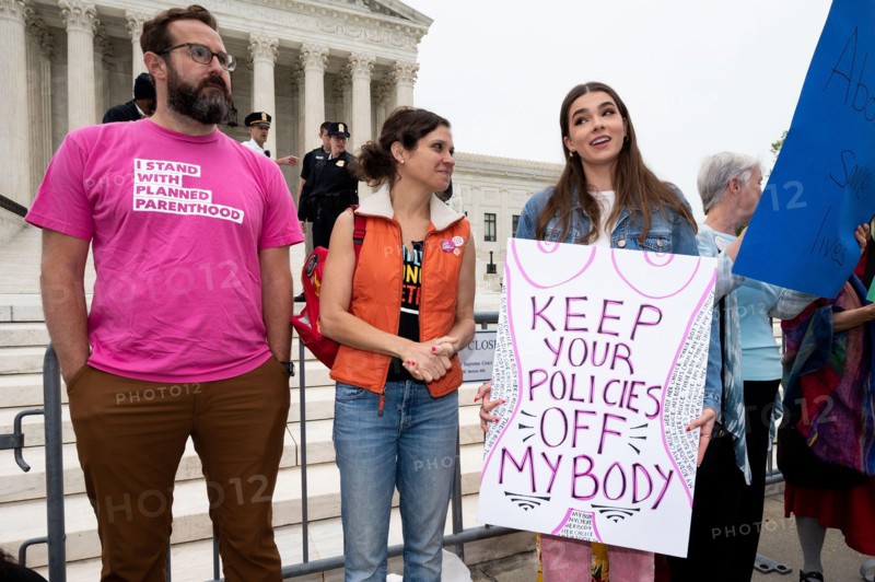 A protester wearing a shirt with words "I stand with Planned Parenthood" stands next to a woman holding a placard reading "Keep your policies off my body" during an abortion related demonstration in front of the Supreme Court.