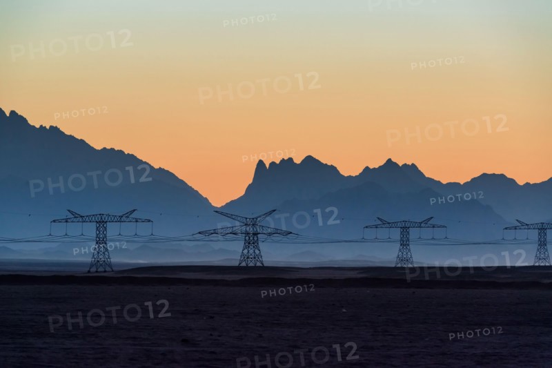 Big powerline in the desert against beautiful evening mountains silhouettes