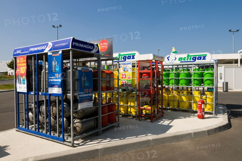 Household gas / gaz bottles in racks at supermarket garage, France.