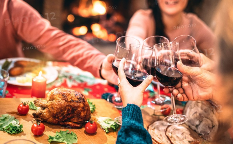 Family toasting red wine and having fun at Christmas supper party - Holiday celebration concept with happy people enjoying winter time together