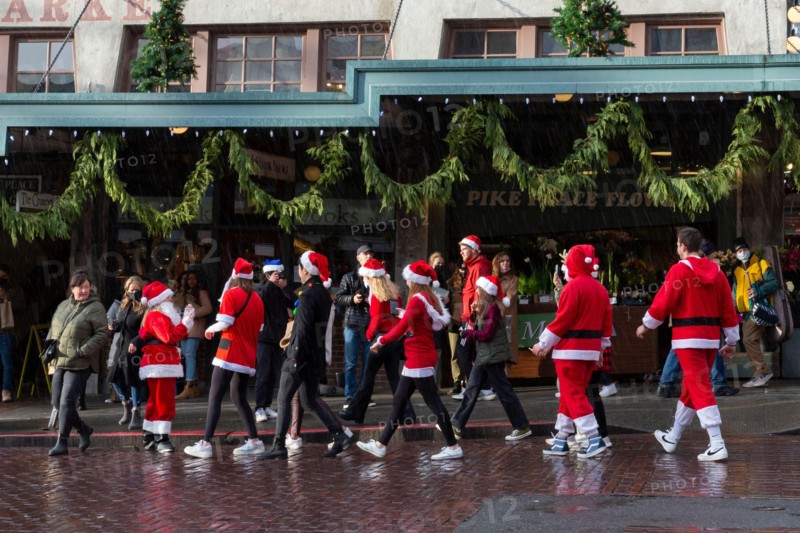 Revelers dressed in holiday themed costumes gather at Pike Place Market during Seattle SantaCon on Saturday, December 11, 2021. The annual pub crawl and fundraiser returned this year after its cancellation in 2020 due to the coronavirus pandemic.