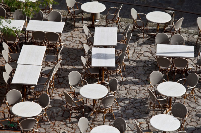 Empty tables at pavement cafe and cobbled pavement in St Emilion, Bordeaux region of France