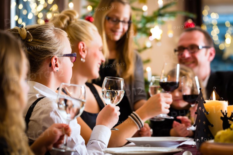 German parents and children toasting with wine and water at Christmas eve dinner