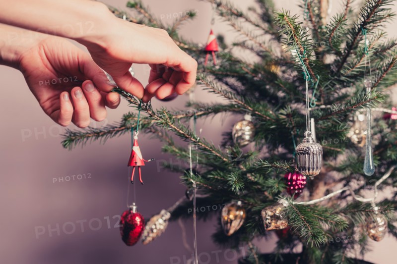 Hands decorating a christmas tree with all kinds of colorful things