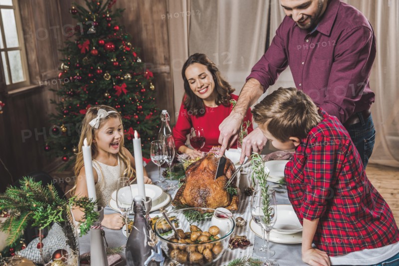 Happy family of four having roasted turkey for Christmas dinner