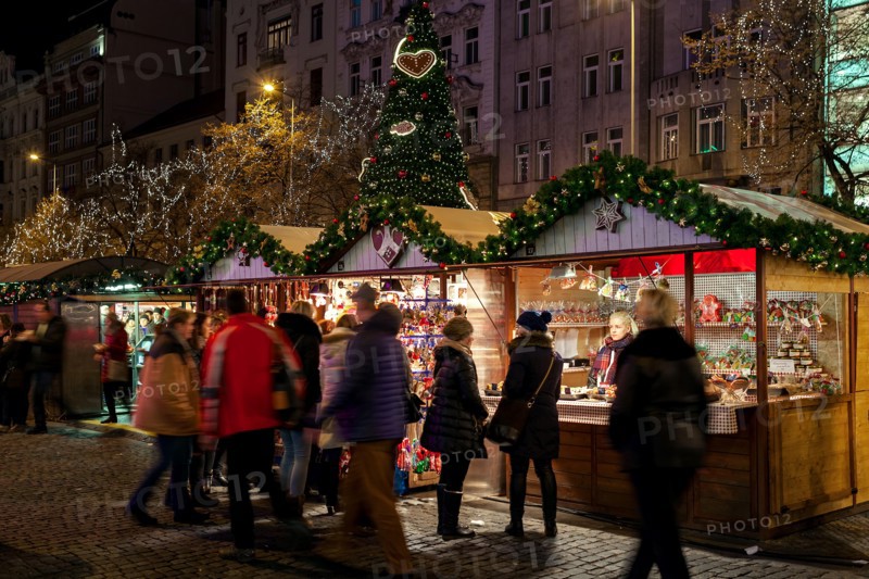 PRAGUE, CZECH REPUBLIC - DECEMBER 10, 2016: People passing by illuminated kiosks with souvenirs and decorations during traditional Christmas market.
