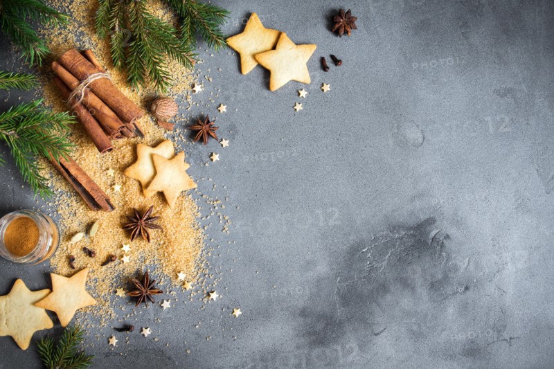 Christmas spices, gingerbread cookies and baking ingredients on grey concrete background. Cinnamon, anise stars, nutmeg, cardamon, cloves, brown sugar