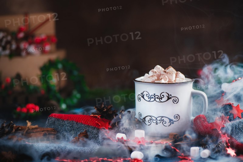 Hot chocolate with marshmallows in a cozy enamel mug with steam and Christmas decorations