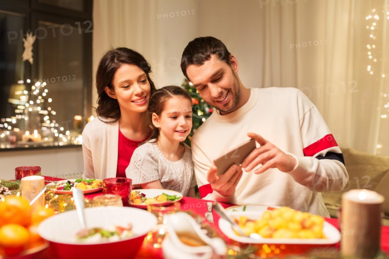 family with smartphone having christmas dinner