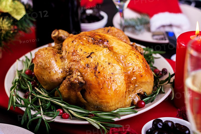 Baked turkey. Christmas dinner. The Christmas table is served with a turkey, decorated with bright tinsel and candles. Fried chicken, table.  Family d
