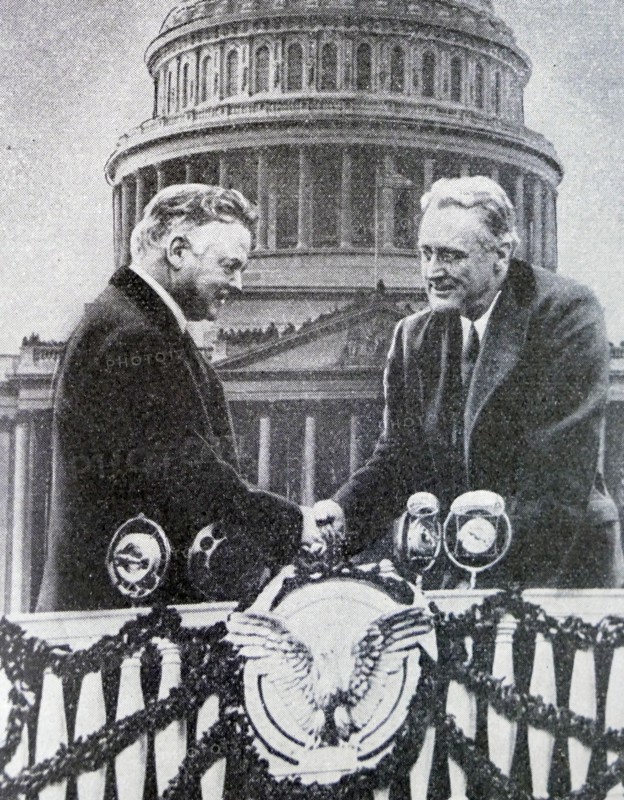 Black and white photo of the new US President Franklin D. Roosevelt (1882-1945) shaking hands in front of the US Capitol Building with the outgoing president, Herbert Hoover (1874-1964). The photo was from Roosevelt's first presidential inauguration on 4 March 1933.