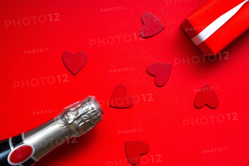 saint valentine day celebration flat lay with a bottle of chapagne and gift on red background