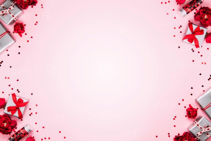 Saint Valentine Day or Mothers day card template, greeting or invitation flat lay for wedding. Top view on pink background with paper gift boxes with red ribbons decorated with heart confetti, shapes
