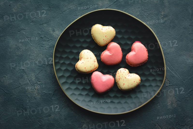 Macarons cakes in a shape of a heart. Small French cakes for Valentines Day. Sweet and colorful french macaroons.