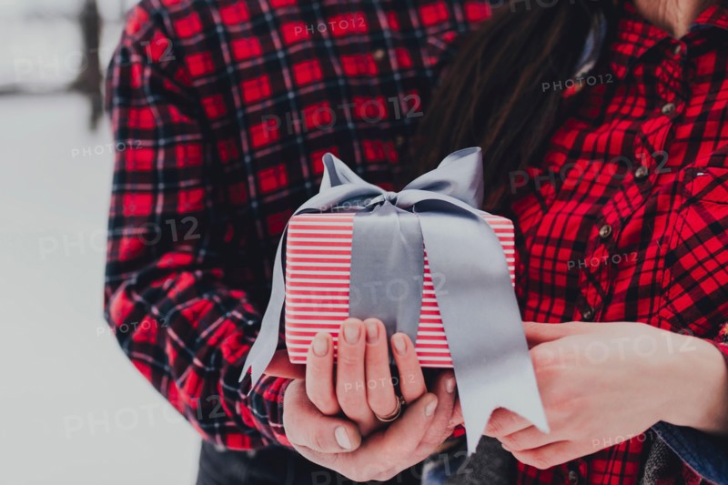 Boyfriend giving a gift box present with ribbon due to Saint Valentine day