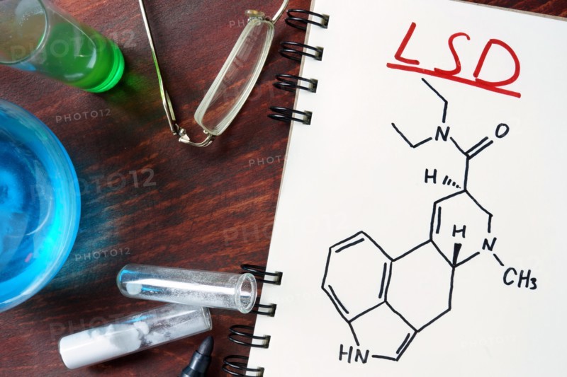 Notepad with chemical formula of LSD on the wooden table. Drugs concept.