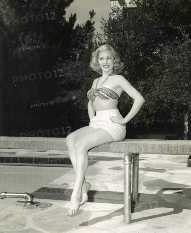 The American actress Lila Leeds with a two piece swimsuit sitting on the trampoline at a swimming pool