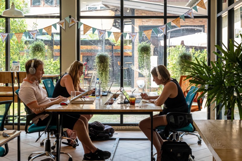 Three people working on laptops at a coworking space