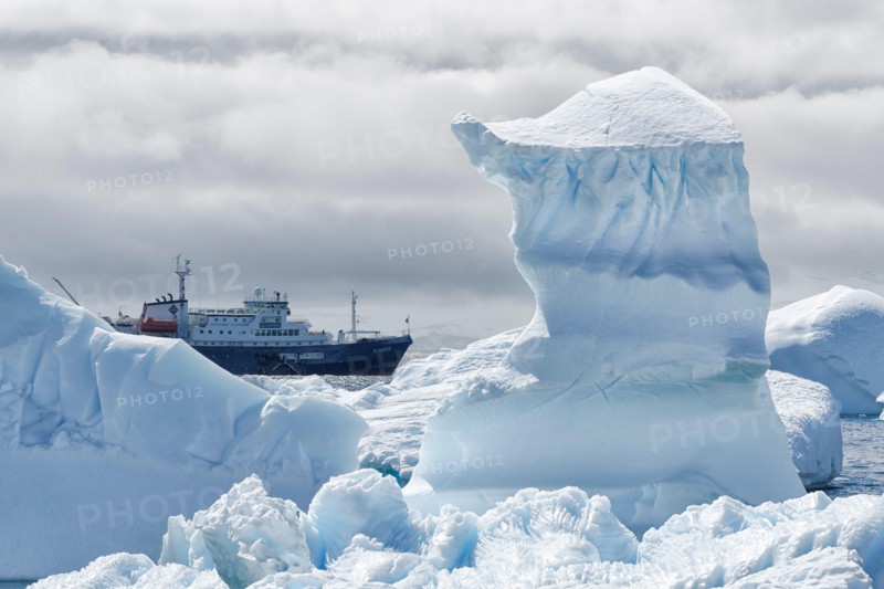 View between two snow peaks to a small cruise ship, Antarctic Peninsula, West Antarktika