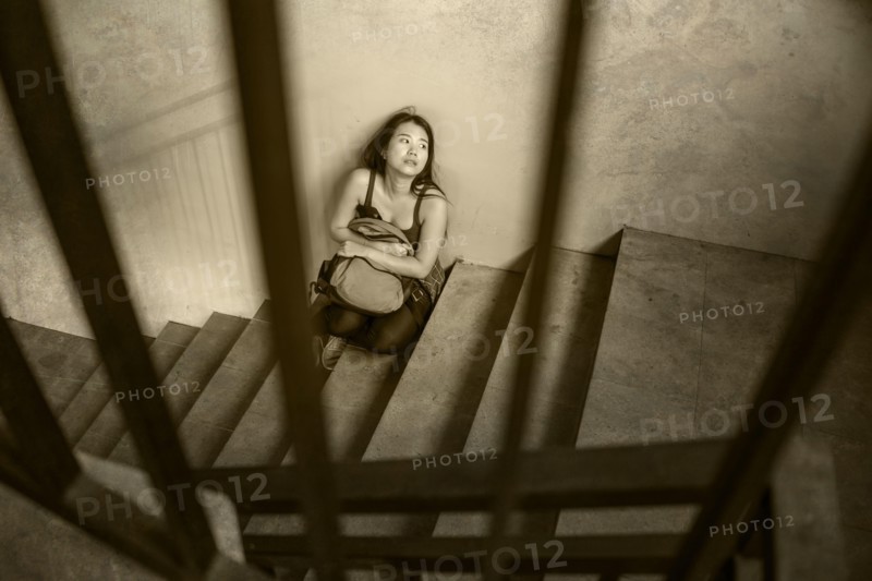 young depressed and scared Asian Korean student girl suffering abuse and harassment at school victim of bullying and discrimination sitting on college