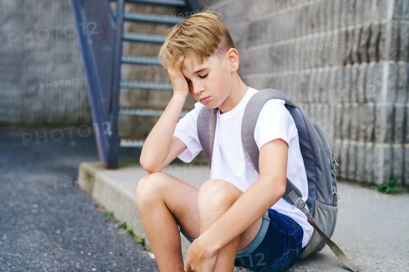 very sad boy bullying in school playground.