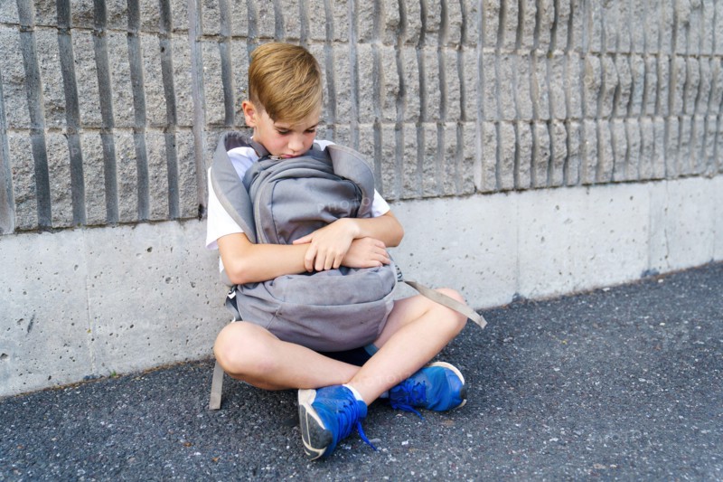 very sad boy bullying in school playground.