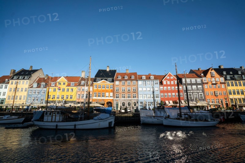 The colourful streets of Copenhagen, Denmark, along Nyhavn Quayside, on a sunny day with a blue sky.
