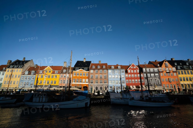 The colourful streets of Copenhagen, Denmark, along Nyhavn Quayside, on a sunny day with a blue sky.