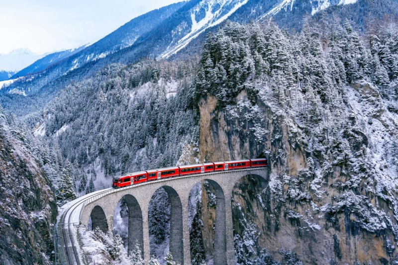 Aerial view of Train passing through famous mountain in Filisur, Switzerland. Landwasser Viaduct world heritage with train express in Swiss Alps snow