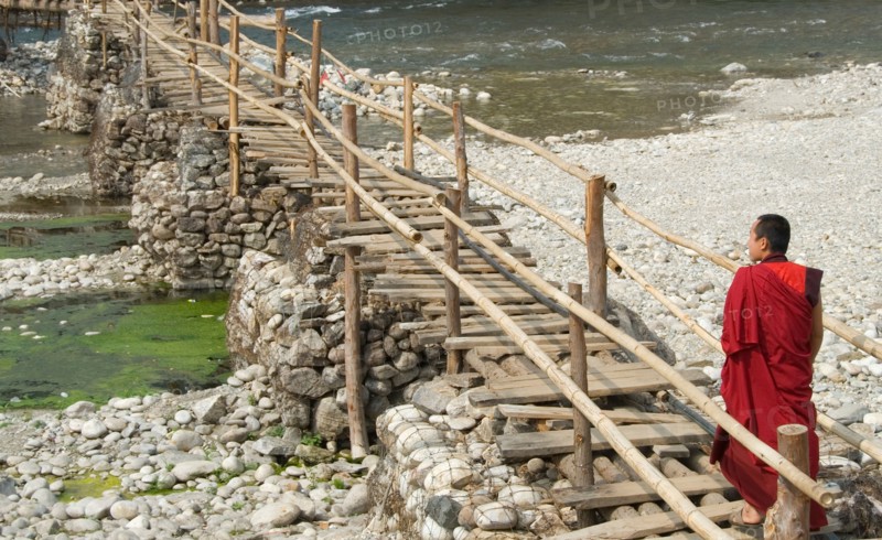 Monk walking to village from Punakha Dzong along temporary bamboo suspension bridge over Mo Chhu (Mother River), Bhutan