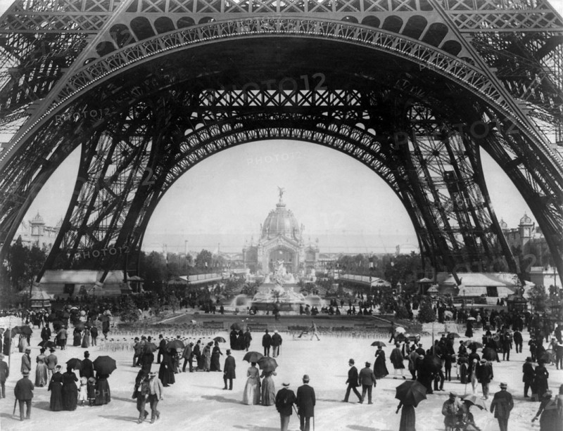 Paris Exposition, view from ground level of the Eiffel tower with Parisians promenading, 1889