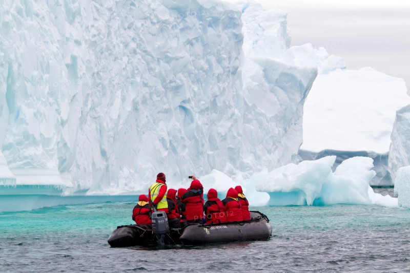 Antarctica cruise tourism with cruise ship passengers in zodiac boat viewing Antarctic glacier and iceberg, icebergs.