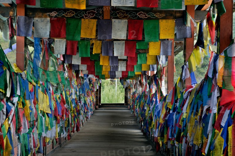 BHUTAN - Prayer flags cover the inside of the Kundeyling Baazam (a cantilever pedestrian bridge) crossing the Wang Chhu (river).