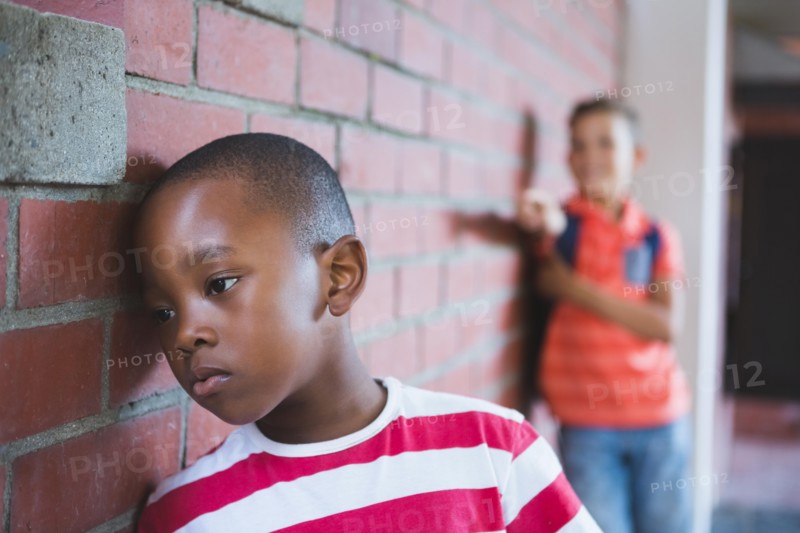 Schoolkid bullying a sad boy in corridor