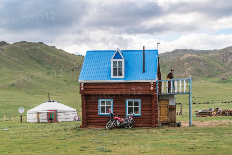 Mongolian man on the terrace of his wooden house. Tariat district, North Hangay province, Mongolia.