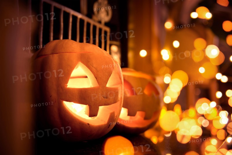 Halloween pumpkins at home on a fireplace with sparkling lights. Cosy autumn background.