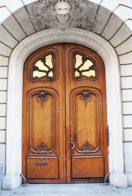 Old fashioned front door entrance, white facade and brown door, Paris, France
