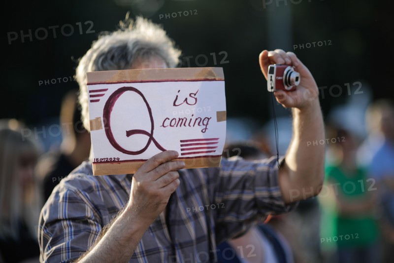 Bucharest / Romania - July 15, 2020: A man takes part at a protest and displays a Qanon message on a cardboard.
