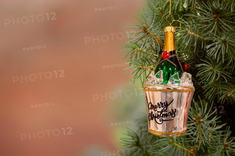 Christmas ornament champagne bottle in a bucket of ice hanging from a fir tree. Copy space.