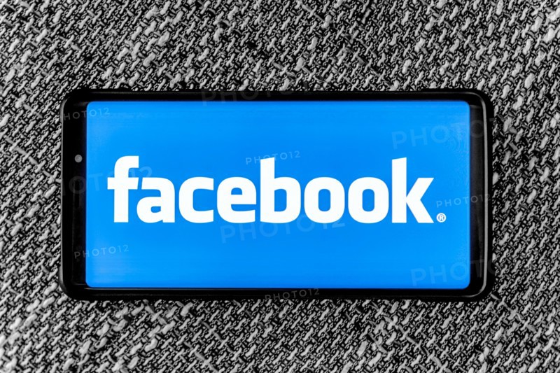 Facebook page on the smartphone on fabric background. Facebook is very well know social networking service founded in 2004 by Mark Zuckerberg