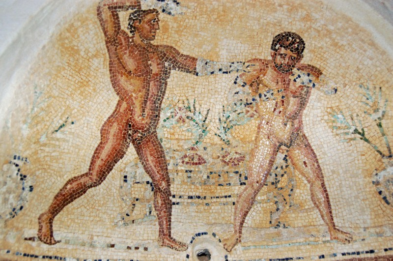 Ancient Roman mosaic showing one man soaping the other.  Arched niche in the baths of the Villa Silene, also known as Villa Celine, in the Khoms area
