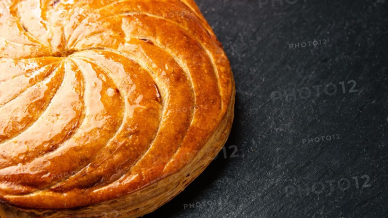 Epiphany cake or galette des rois in French on black slate background