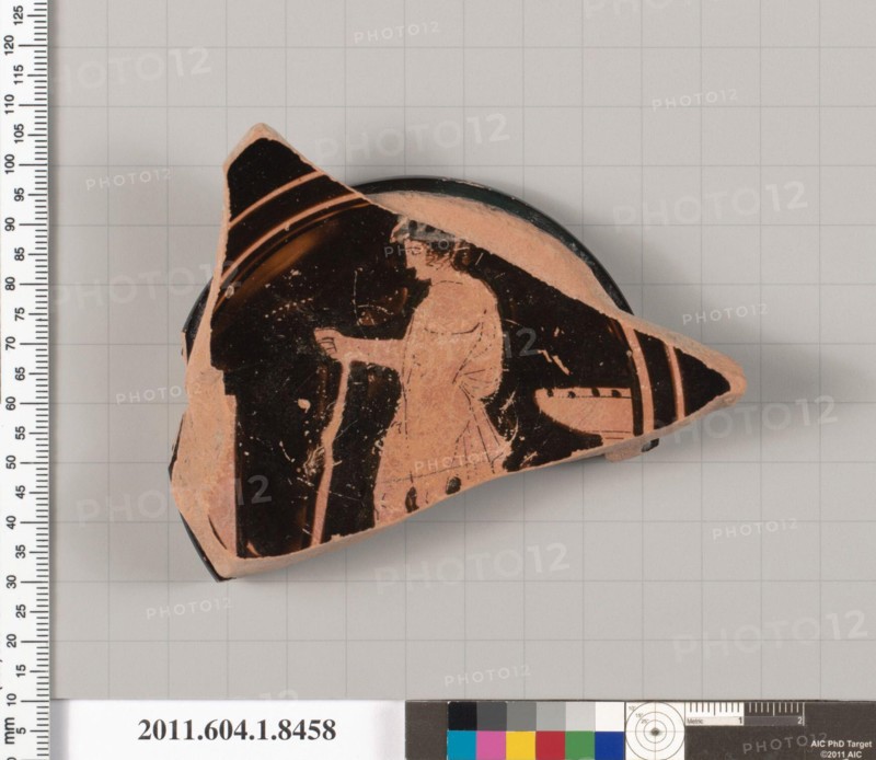Terracotta fragment of a stemless kylix (drinking cup) 460–450 B.C. Greek, Attic Interior, wreathed youth to left, with his himation draped over his right shoulder and around his right arm, holding a staff in his right hand; behind him, a laver; in front of him, a goal post?; Exterior, profiled ring foot, with an unglazed resting surface; the inner wall of the foot is glazed; the underside of the floor is decorated with concentric circles; the outer ring is in reserve, followed by a band of black glaze, a thin band reserve, a thin black glaze ring, and a wide band of reserve; the central band
