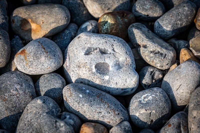 A high angle view of pebbles on a beach with one looking like a face with  a shocked look