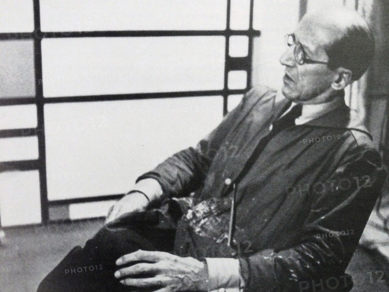 Photograph of the famous Dutch artist Piet Mondrian (7th March 1872 - 1st February 1944). He is shown seated infront of one of his pieces of work. The photograph was taken around 1942.