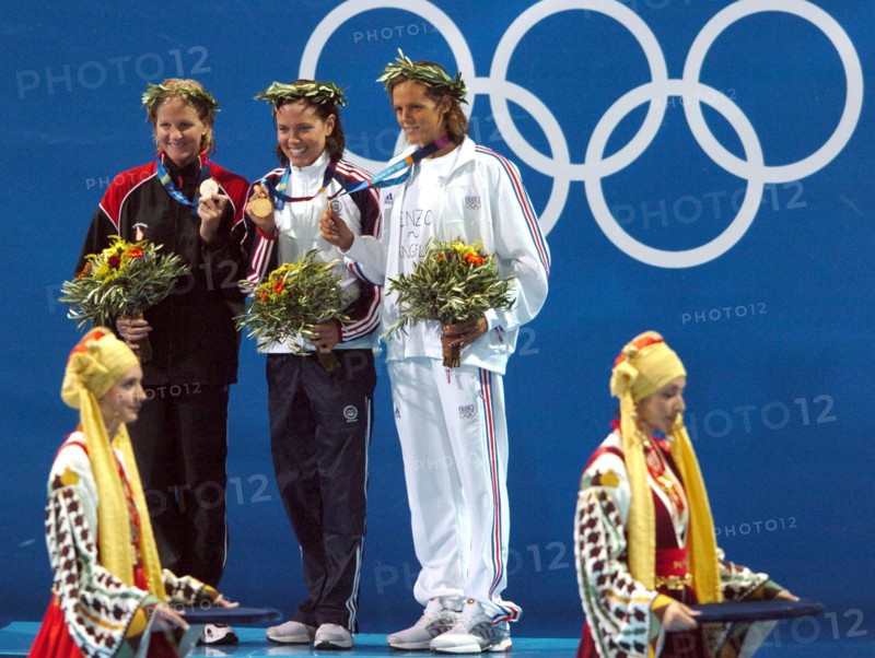 KRT SPORTS STORY SLUGGED: OLY-SWIMMING KRT PHOTO BY KARL MONDON/CONTRA COSTA TIMES (August 16) ATHENS, GREECE  -- Gold medalist Natalie Coughlin, center, stands with silver medalist Kirsty Coventry of Zimbabwe and bronze medalist Laure Manaudou of France after the 100-meter backstroke on Monday, August 16, 2004, during the 2004 Olympic Games in Athens, Greece. (gsb) 2004 (Credit Im