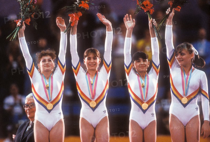 Romanian Gymnastics Team stands on victory stand with gold medals for winning team competition at 1984 Olympic Games in LA