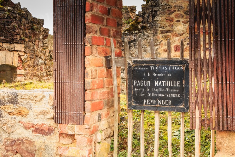 ORADOUR SUR GLANE, FRANCE - December 03, 2017 : commemorative tag on the remains in ruins of the THOMAS-RAGON bakery where it is written - In memory o